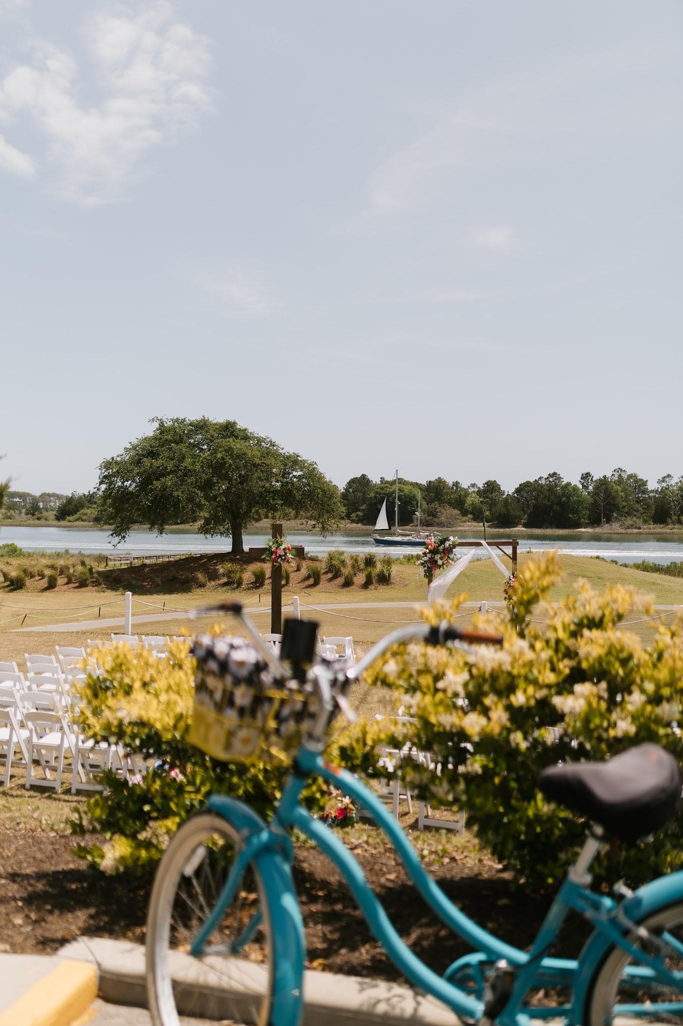 The waterfront wedding ceremony site framed through a blue beach cruiser at The Links at Brick Landing in Ocean Isle Beach, NC